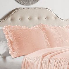 a bed with pink sheets and pillows on it