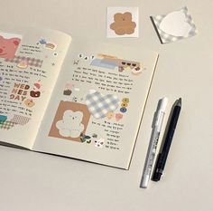 an open book with stickers on it next to a pen and paper cutouts