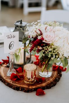 a centerpiece with flowers and candles is displayed on a wood slice at the head table