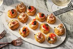 a white plate topped with mini pastries on top of a table next to utensils