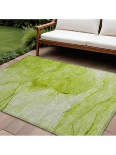 a green area rug on the ground in front of a couch and some plants with white pillows