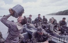 a group of men on a boat in the water with one man drinking from a can