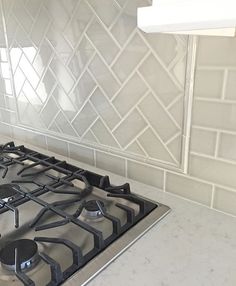 a stove top oven sitting inside of a kitchen next to a wall with white tiles on it