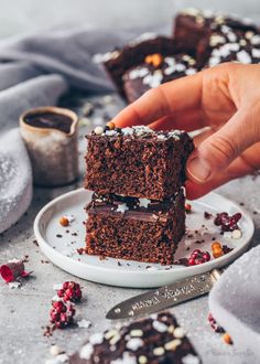 two pieces of chocolate brownie on a plate with cranberries and powdered sugar