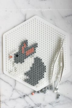 a close up of a crafting board with beads and scissors next to it on a marble surface