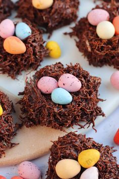 chocolate birds nests with candy eggs on a white plate next to other candies