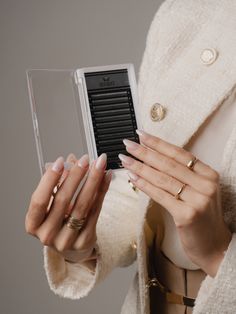 a woman in a white coat holding an electronic device with her hands on the cover