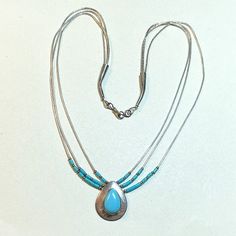 A really gorgeous vintage Native American hand made pendant with liquid silver strands and natural turquoise, circa 1980s.  Hand crafted by Zuni craftsperson Sensa Eustace. The necklace is about 19 inches long.  Three strands of liquid sliver with sterling tube beads, little spacer beads, and heishi turquoise beads.  Teardrop shaped pendant is about 7/8 of an inch long by about 3/4 of an inch wide at its widest point.  Teardrop shaped piece of bright natural turquoise.  The back of the pendant i Silver Strand, Liquid Silver, Tube Beads, Turquoise Pendant, Natural Turquoise, Bead Caps, Turquoise Beads, Spacer Beads, Vintage Necklace