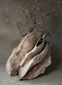 a vase with branches in it sitting on top of a table next to a wall