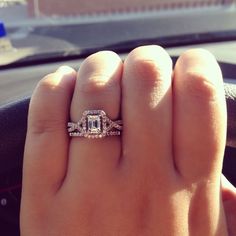 a woman's hand holding a diamond ring in the middle of her fingers while driving