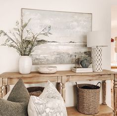 a living room filled with furniture and a large painting on the wall above it's console table