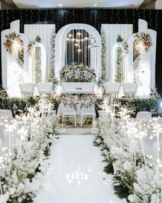 an indoor wedding ceremony with white flowers and greenery