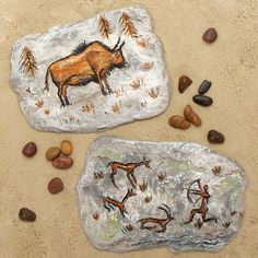 two rock paintings with animals on them and rocks in the sand next to each other