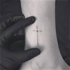 a person holding their foot with a cross tattoo on the side of his foot, in black and white