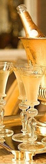 champagne being poured into wine glasses on a gold plated serving platter with silverware