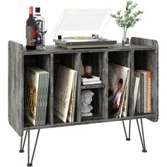 an old record player is sitting on top of a bookcase with books and magazines