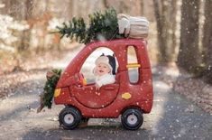 a baby in a red car with a christmas tree on the roof and an advertise