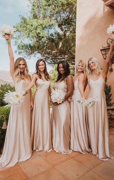 the bridesmaids are all dressed in champagne colored gowns and holding their bouquets