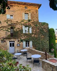 an outdoor patio with tables and chairs next to a stone building covered in ivys