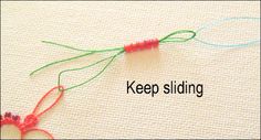 the words keep sliding are written in red and green yarn on a white surface with two crochet hooks