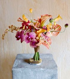 a vase filled with lots of colorful flowers on top of a blue table next to a wall