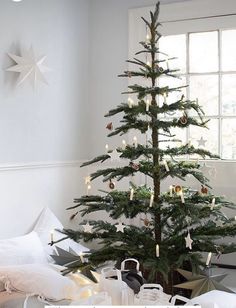 a small christmas tree in the corner of a room with white sheets and pillows on the floor