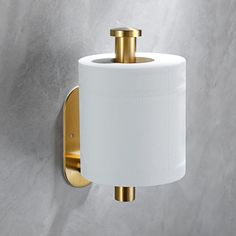 a white toilet paper roll hanging from a gold - plated metal wall mounted holder