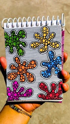 a hand holding a notebook with colorful flowers on it