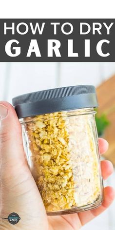 a person holding a jar filled with granola in their hand and text overlay reads how to dry garlic