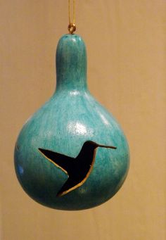 a blue ceramic ornament with a bird on it's side hanging from a gold chain