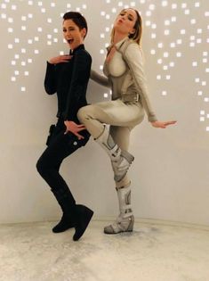 two people dressed in futuristic garb and boots posing for the camera with their arms around each other