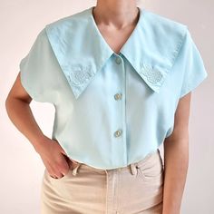 Gorgeous vintage blouse in aqua blue with beautiful chelsea collar. It has short dolman sleeves, floral collar embellishment and five round buttons. It is made from a lightweight and smooth polyester fabric. Perfect blouse for everyday or special occasions. Made by C&A. 100% polyester. Labelled as size 16 UK, 40, would Medium to Large size. Measurements when laid flat are: Pit to pit: 52cm Waist: 50cm Hemline: 54cm Length: 61cm. Excellent condition. B. Blue Collared Blouse For Spring, Fitted Tops With Buttons And Cute Collar, Fitted Top With Buttons And Cute Collar, Fitted Top With Buttons And Collar, Light Blue Fitted Top With Collar, Spring Tops With Peter Pan Collar And Buttons, Chic Tops With Peter Pan Collar And Buttons, Summer Collared Top With Buttons, Chic Top With Peter Pan Collar And Buttons