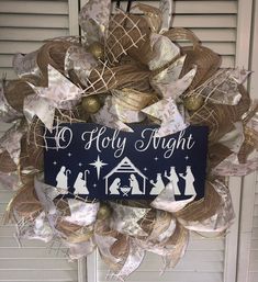 a wreath with nativity scene on it hanging from the side of a house door