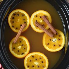 orange slices and cinnamon sticks in a slow cooker filled with hot water for winter