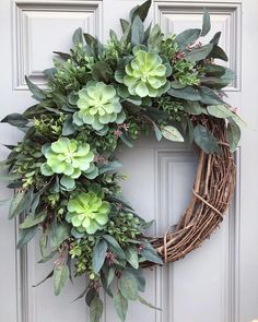 a wreath with green flowers and greenery is hanging on the front door's side