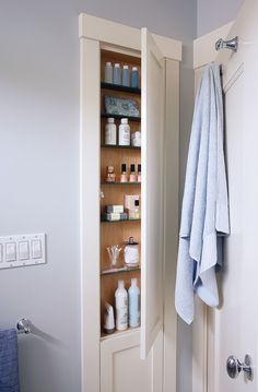 a towel hanging on the wall next to a cabinet with bottles and soaps in it