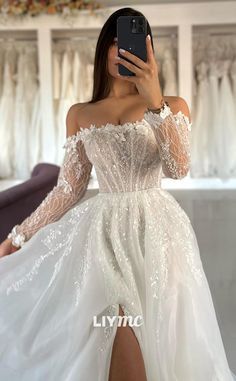 a woman taking a selfie wearing a white dress with sheer sleeves and thigh high slit