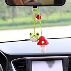 two crocheted mushrooms hanging from the dashboard of a car