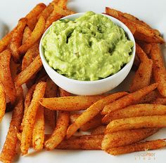 a white plate topped with french fries covered in guacamole