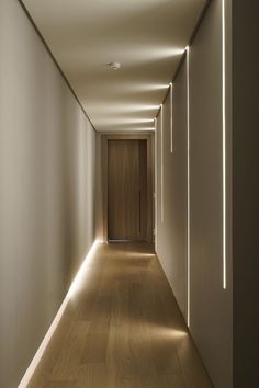 an empty hallway with light coming in from the door and lights on the wall behind it