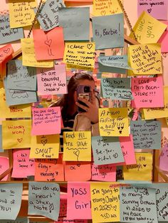 a woman taking a selfie with her cell phone surrounded by post it notes