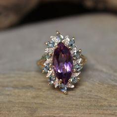 an oval shaped amethorate and diamond ring on top of a piece of wood