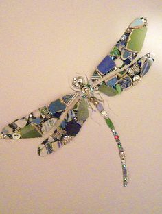 a dragonfly brooch sitting on top of a white table next to a wall