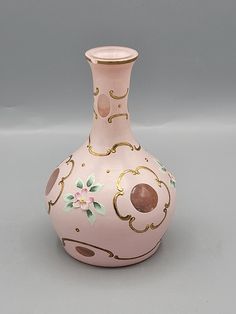 a pink and gold vase sitting on top of a white table next to a gray wall