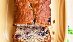 a loaf of blueberry banana bread cut into slices on a yellow plate with green leaves