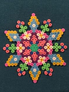 a snowflake made out of plastic beads on a black tablecloth with blue background