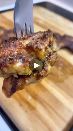 a piece of meat on a cutting board with a knife and fork sticking out of it