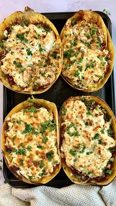 four pizzas with cheese and herbs in them on a baking tray, ready to be eaten