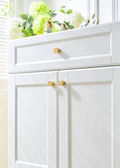 a white cabinet with gold handles and knobs