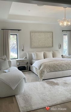 a large white bed sitting in a bedroom next to two windows